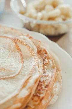 Pancake baking process. Ready-made pancakes on a white plate. Stock Photos