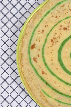 Pancake with green spiral pattern on a checkered tablecloth Stock Photos