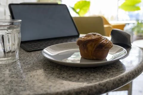 Pancake or cupcake on ceramic plate, terrazzo table, tablet in the back. En.. Stock Photos