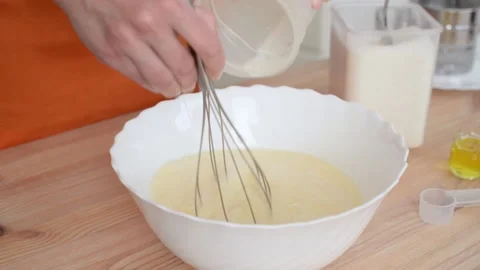 Pancake recipe, adding milk to the dough mixture and stirring it. Stock Footage 194565944
