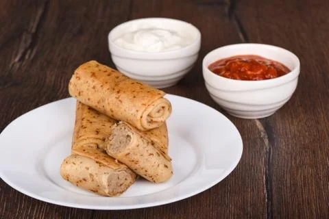 Pancake rolls with meat filling, served with sour cream and ketchup sauce Stock Photos