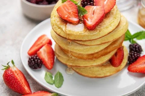 Pancake stack with fresh strawberries, blackberries, and dripping honey Stock Photos