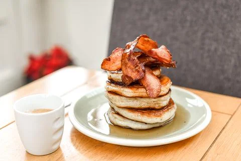 Pancake stack with golden syrup and a large portion of bacon as a breakfast o Stock Photos