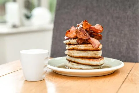 Pancake stack with golden syrup and a large portion of bacon as a breakfast o Stock Photos