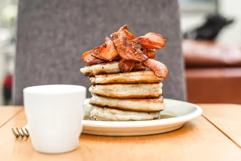 Pancake stack with golden syrup and a large portion of bacon as a breakfast o Stock Photos