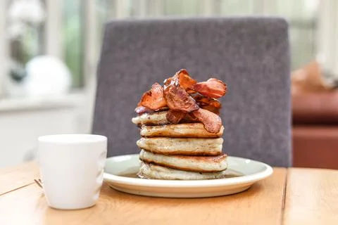 Pancake stack with golden syrup and a large portion of bacon as a breakfast o Stock Photos