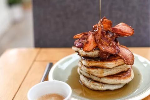 Pancake stack with maple syrup and a large portion of bacon as a breakfast or Stock Photos