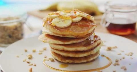 Pancake stack sitting on kitchen table with banana slices and syrup, with Stock Photos