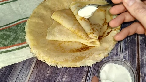 Pancakes.  Adding sour cream to pancakes with a spoon Stock Footage 232945766