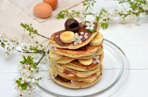 Pancakes and branches of blossoming cherry on the table Stock Photos
