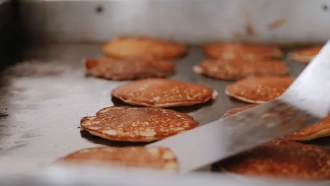 Pancakes are cooking on large baking sheet and chef turns over round pancake Stock-Footage 111461639