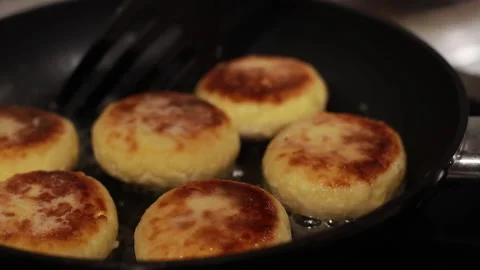 Pancakes are fried in a frying pan, the cook mixes the food in a frying pan with Stock Footage 166644853