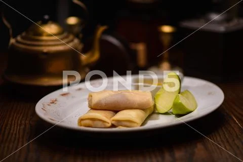 Pancakes with a filling and a green apple, in the background a kettle Stock Photos