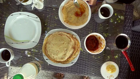 Pancakes On Plates, Jam and Coffee On A Table, Hands Put Jam With Spoon Stock Footage 98771982
