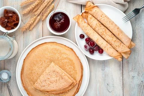 Pancakes in a stack and a portion in a separate plate on a light background. Stock Photos