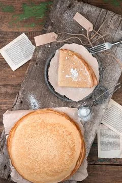 Pancakes in a stack and a portion sprinkled with powdered sugar on a wooden Stock Photos