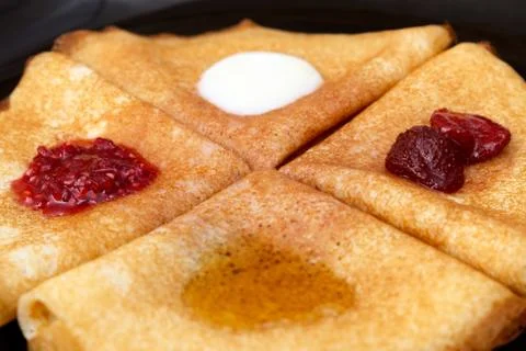 Pancakes with strawberry jam, raspberry jam , sour cream and honey Stock Photos
