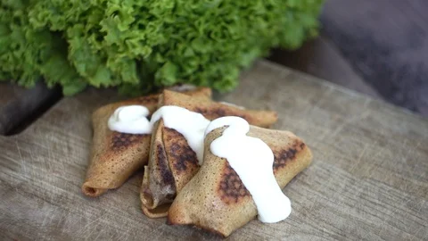 Pancakes stuffed with sour cream, a wooden spoon with sour cream, green lettuce Stock Footage 91928853