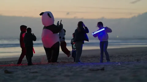 Panda mascot dancing with children on beach at sunset Stock Footage 330497065