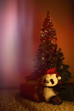 Panda plush under Christmas tree in warm red and orange light Stock Photos