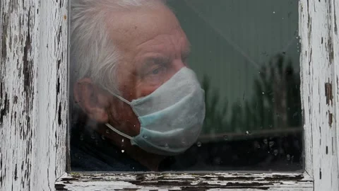 At Pandemic Covid Old Man In Medical Mask Looks Sadness Out Of Window At Street Stock Footage