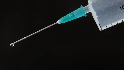 Pandemic vaccine drops falling down from needle edge of the medical syringe. Stock Footage 152767250