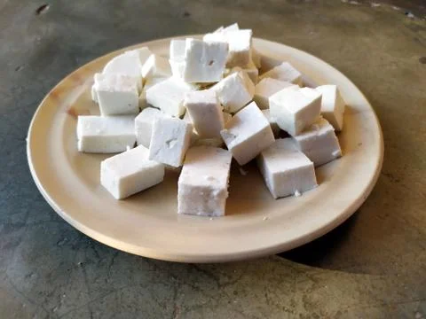 Paneer slice put in a plate with stone background Stock Photos