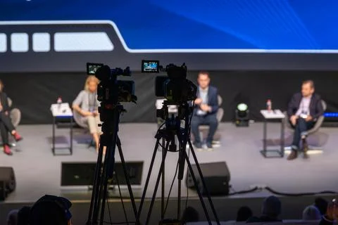 Panel discussion on stage with cameras capturing expert panel and audience Stock Photos