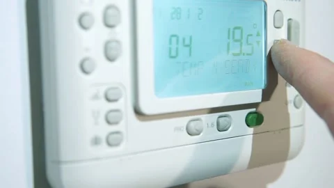 Panel of heating system thermostat. Hand of a person turn down temperature Stock Footage 219435898