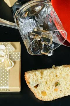 Panettone slice next to a gift box and an overturned glass of whiskey (vertic Stock Photos