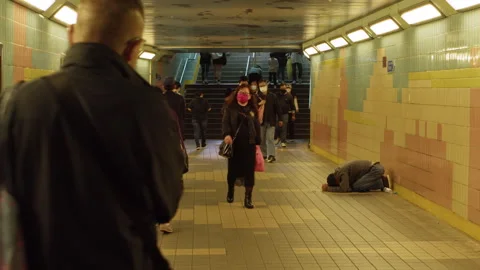 Panhandler bagging for money in a pedestrian tunnel, mandate masking in effect Stock Footage 254646443