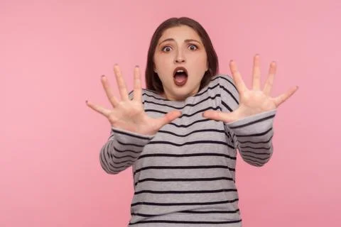Panic and phobia. Portrait of scared woman in striped sweatshirt raising hand Stock Photos