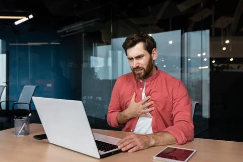 Panic attack in the workplace. A young man sits in the office at the table Foto stock