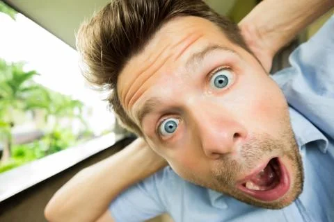Panic man is shocked. His face is close to camera. He is opening his mouth in Stock Photos
