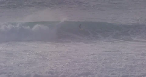 Panning 4K shot of pro surfer riding in tube barrel wave in ocean on misty day Stock Footage 151876235