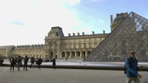 Panning across museum grounds Le Louvre with pyramid during day - Paris France Stock Footage 94063305