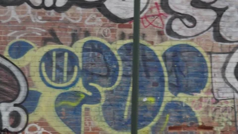 Panning across a red brick wall covered in colorful graffiti Stock Footage 241498500