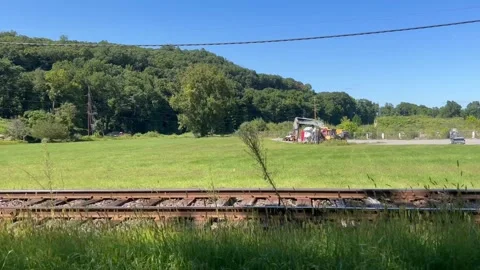 Panning Across Train Tracks And Rural Grassy Field With Parked Excavator Vídeos de archivo 344899476