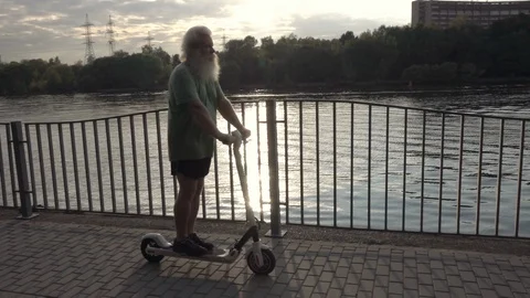 Panning of active senior Caucasian man, going pass on electric scooter Vídeo Stock 121028560