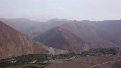 Panning aerial drone view between mountains over a village in the highlands of L 스톡 동영상 199633559