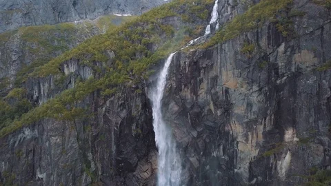 Panning around a stunning dramatic waterfall on a steep vertical cliff Stock Footage 99680998