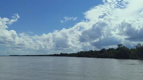 Panning of a beautiful cloudy sky and sun rays from the white cloud, river. Video stock 221114702