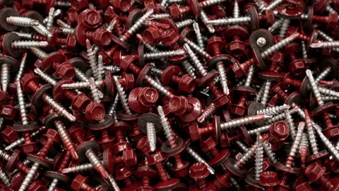 Panning of camera down a large number of red screws 4K. Background for text. Stock Footage 98322399