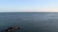 Panning from a clear sky down to a little rock island just off the coast HD Footage