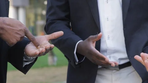 Panning close-up of hand gestures being made between business men at an outdoor Stock Footage 124079182