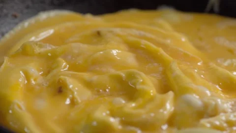 Panning Close Up of Scrambled Eggs Being Cooked in a Pan During Breakfast 스톡 동영상 347758130