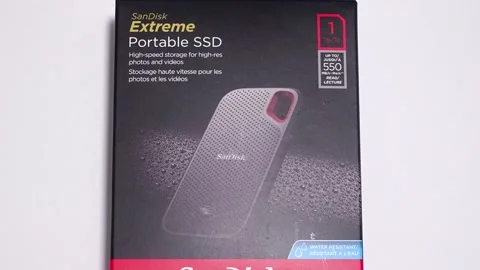 Panning down on a SanDisk SSD Drive box on a white background.store. 스톡 동영상 157503935