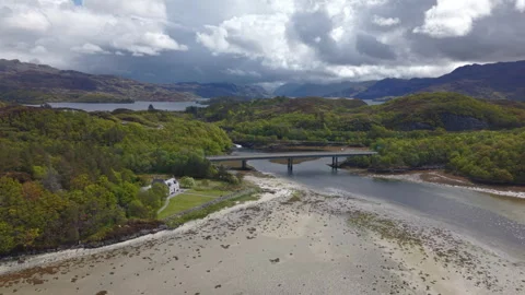Panning drone shot showcasing the Morar Bridge, tidal river channel, and coastal Video stock 336609614