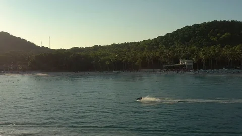 Panning left by drone following fast moving jet ski on sea water in sunset in fr Stock Footage 124416181
