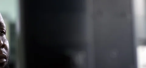 Panning Left: Middle aged African man looking at a desktop monitor as he works Stock Footage 112142309